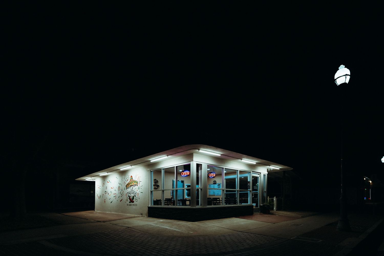 White retro diner building lit up at night with fluorescent lights.