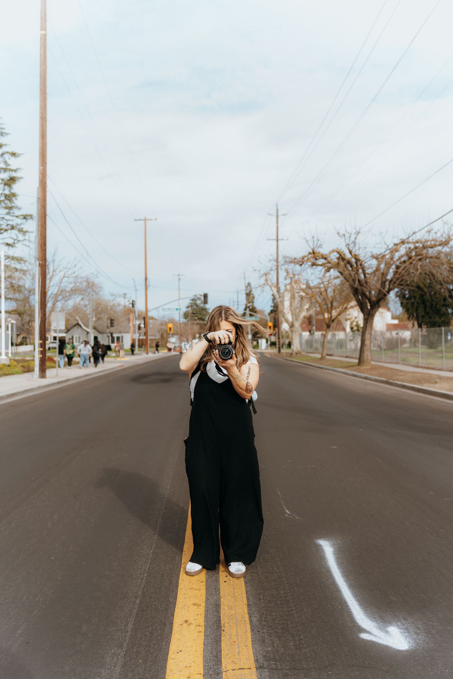 Person taking photos while standing in middle of empty suburban street.