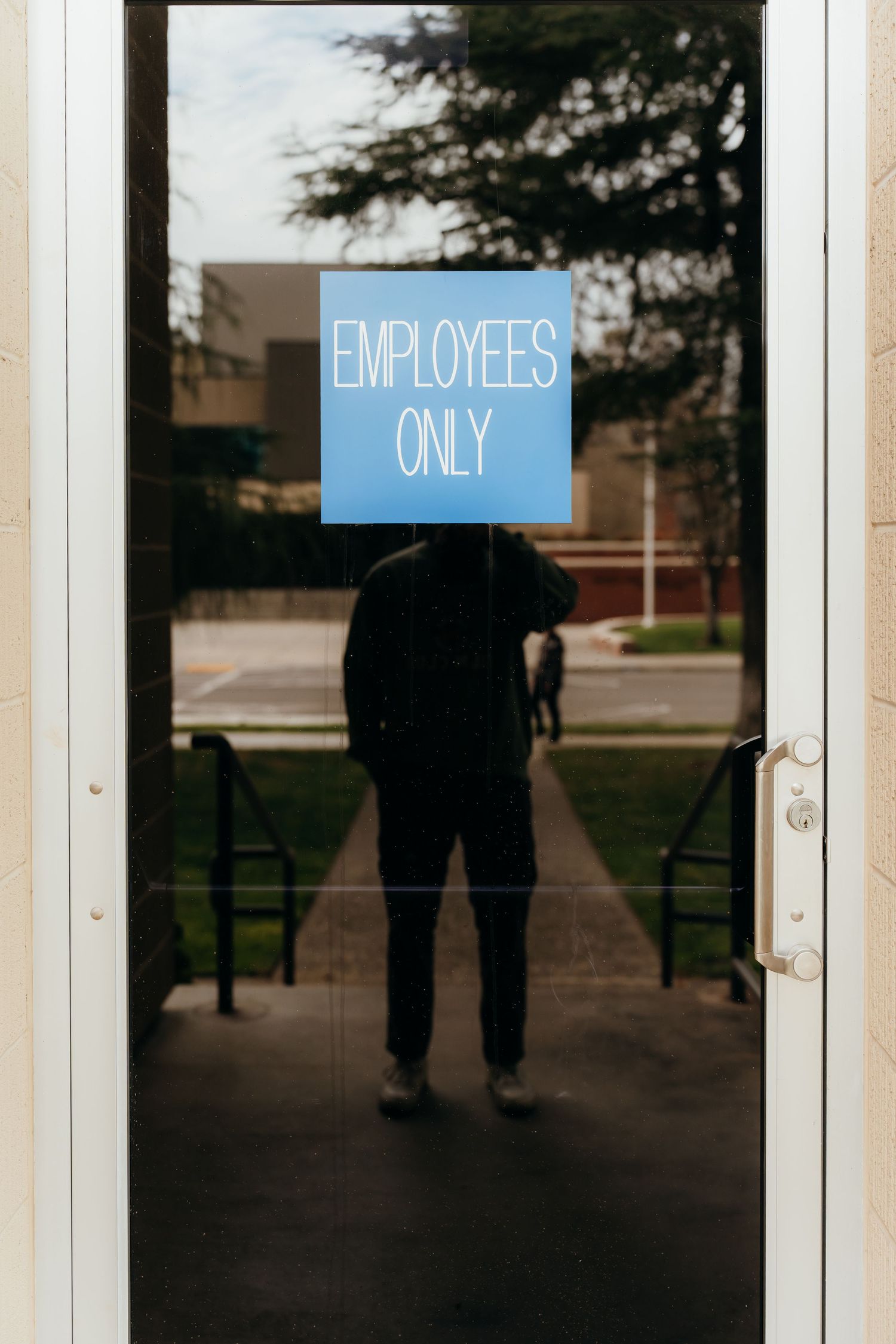 Silhouette of person standing in doorway with blue 'Employees Only' sign above.