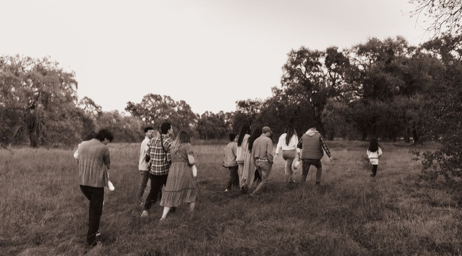 People walking together through a grassy field in black and white photography.