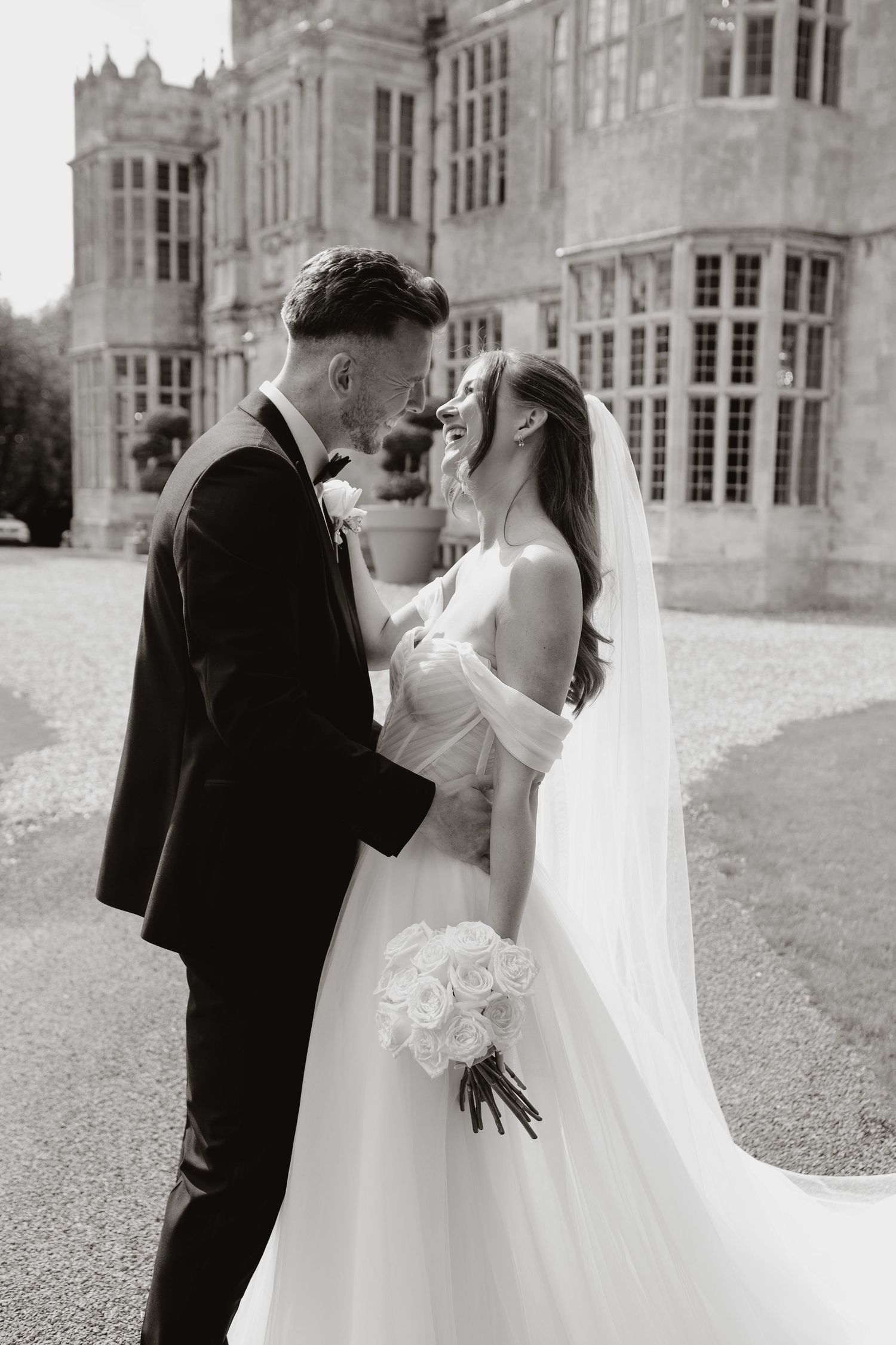 A romantic wedding photography sequence showing the bride and groom in a tender embrace outside a grand stone mansion.