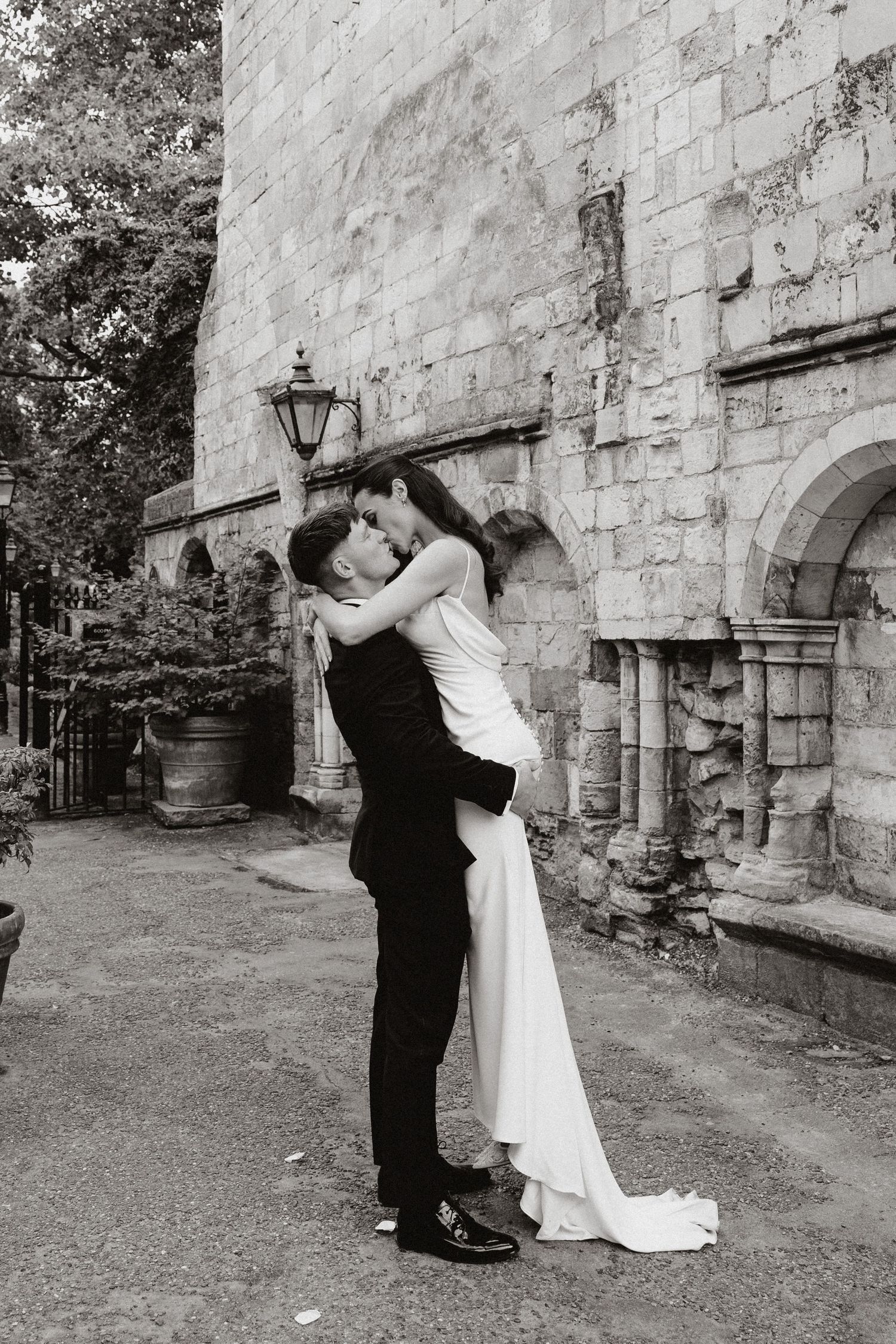 A romantic black and white photo sequence shows a couple in wedding attire embracing against a stone wall.