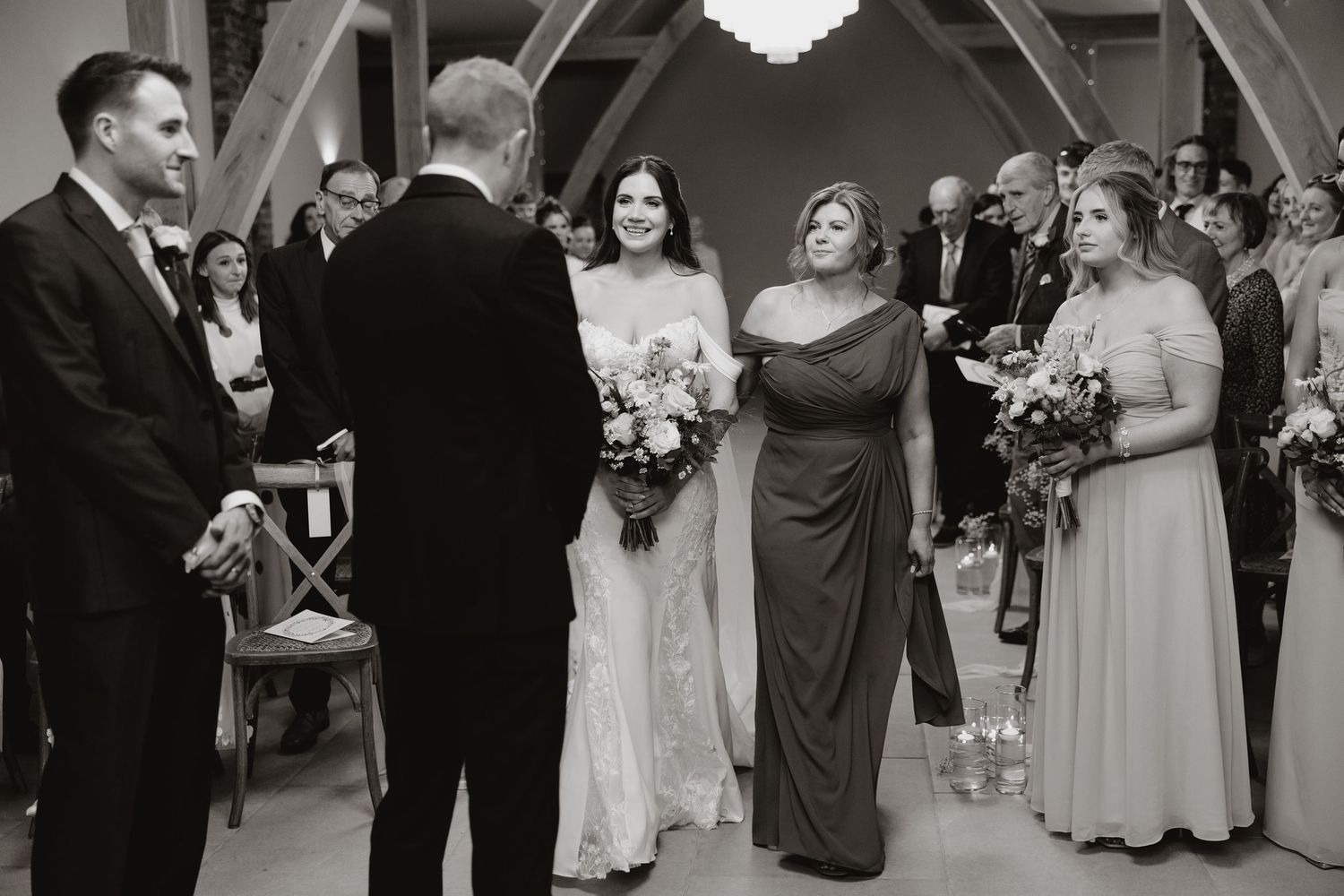 Wedding guests dance and celebrate during a reception in an elegant venue with a chandelier overhead.