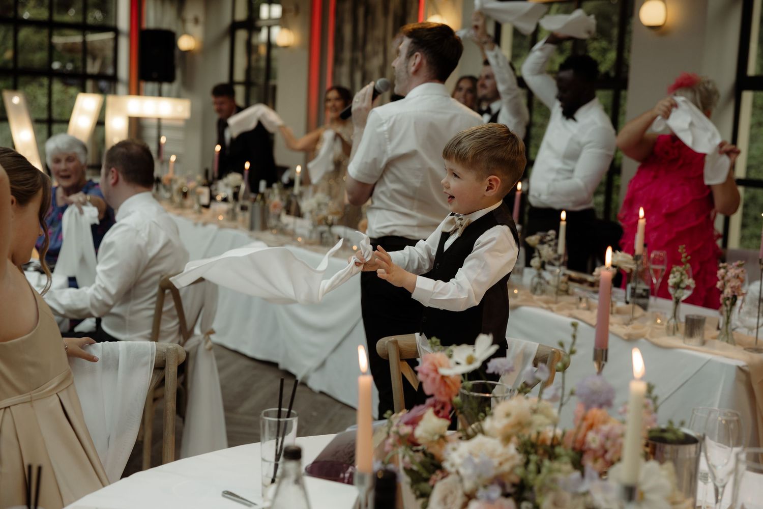 Elegant wedding reception dinner table with candles and floral centerpieces in a formal dining room setting.