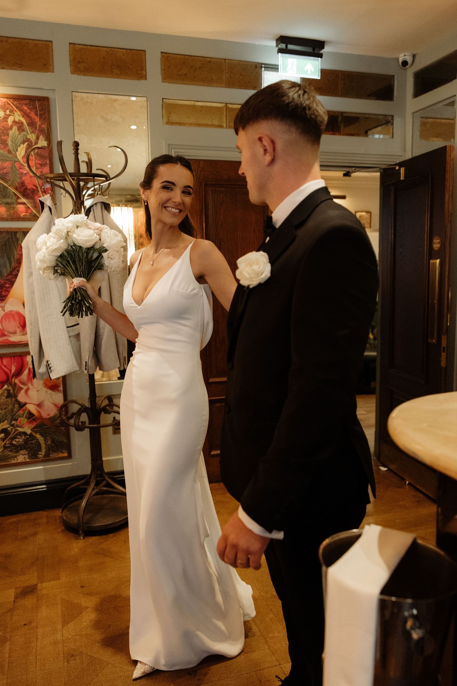 A couple shares a romantic dance moment in a reception hall with wooden floors and elegant decor.