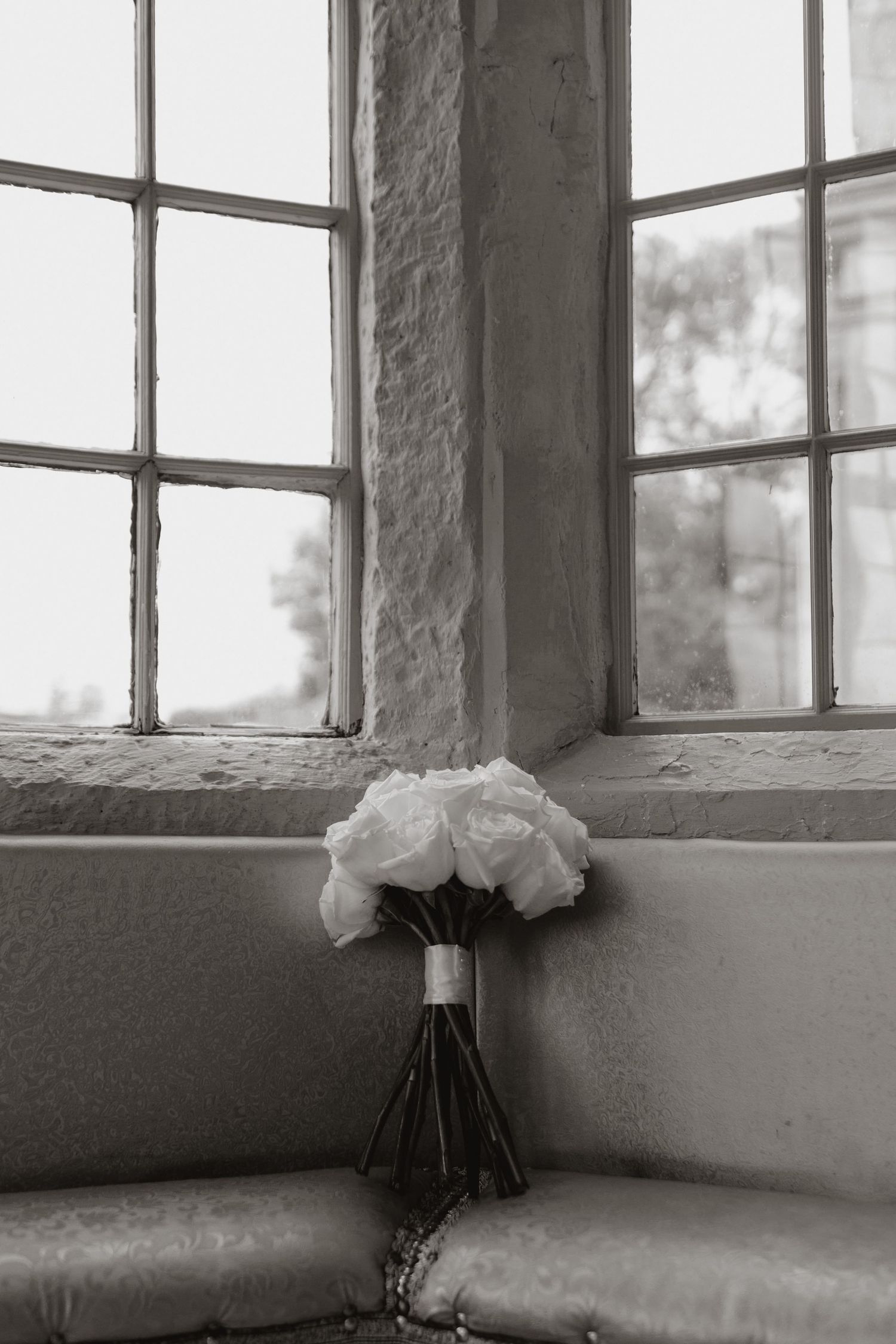 A collection of monochromatic minimalist window photographs showing white flowers on windowsills in a sequence.