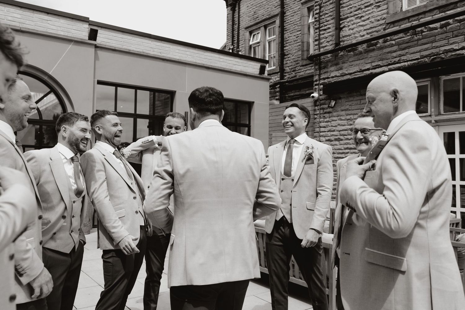 A vintage black and white photo shows a group of men in suits standing together at a social gathering.