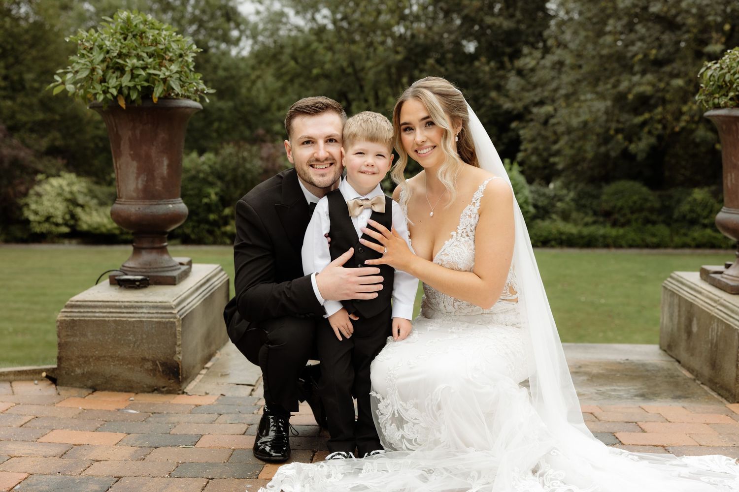 Newlywed couple embraces and shares tender moments during outdoor wedding photo session in garden setting.