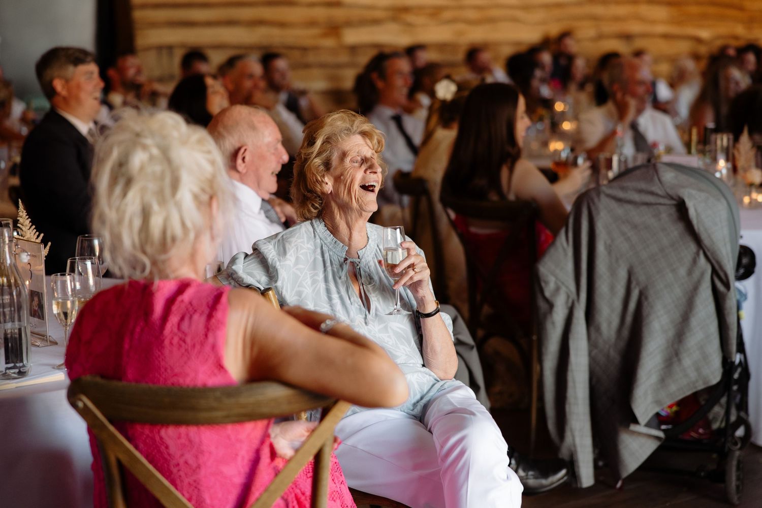 Wedding guests dance and celebrate together on a rustic wooden dance floor at an indoor reception venue.