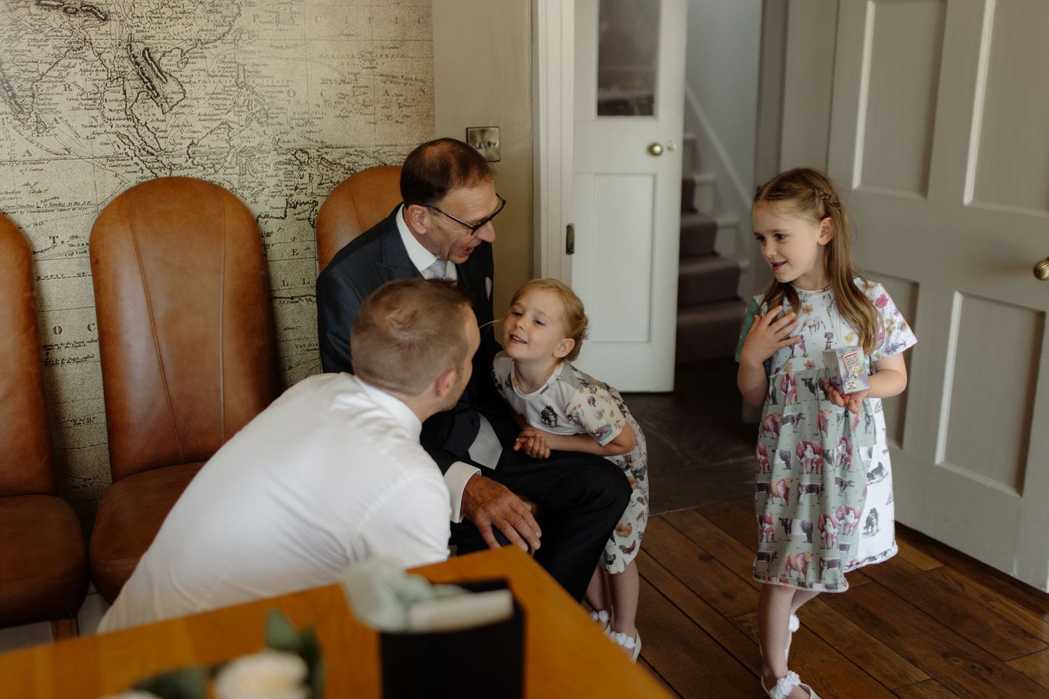 Family members gather around a dining room table with leather chairs for a special celebration moment.