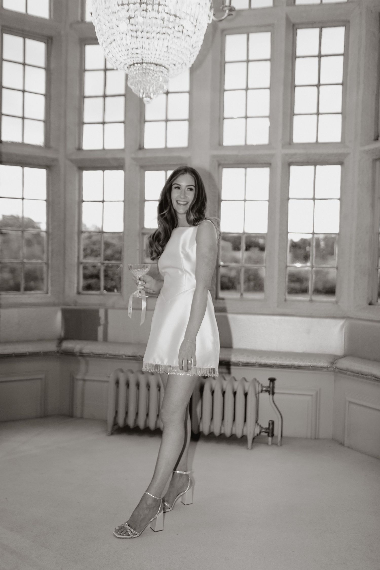 Black and white photo series showing progressive movement across an elegant room with large windows and crystal chandeliers.