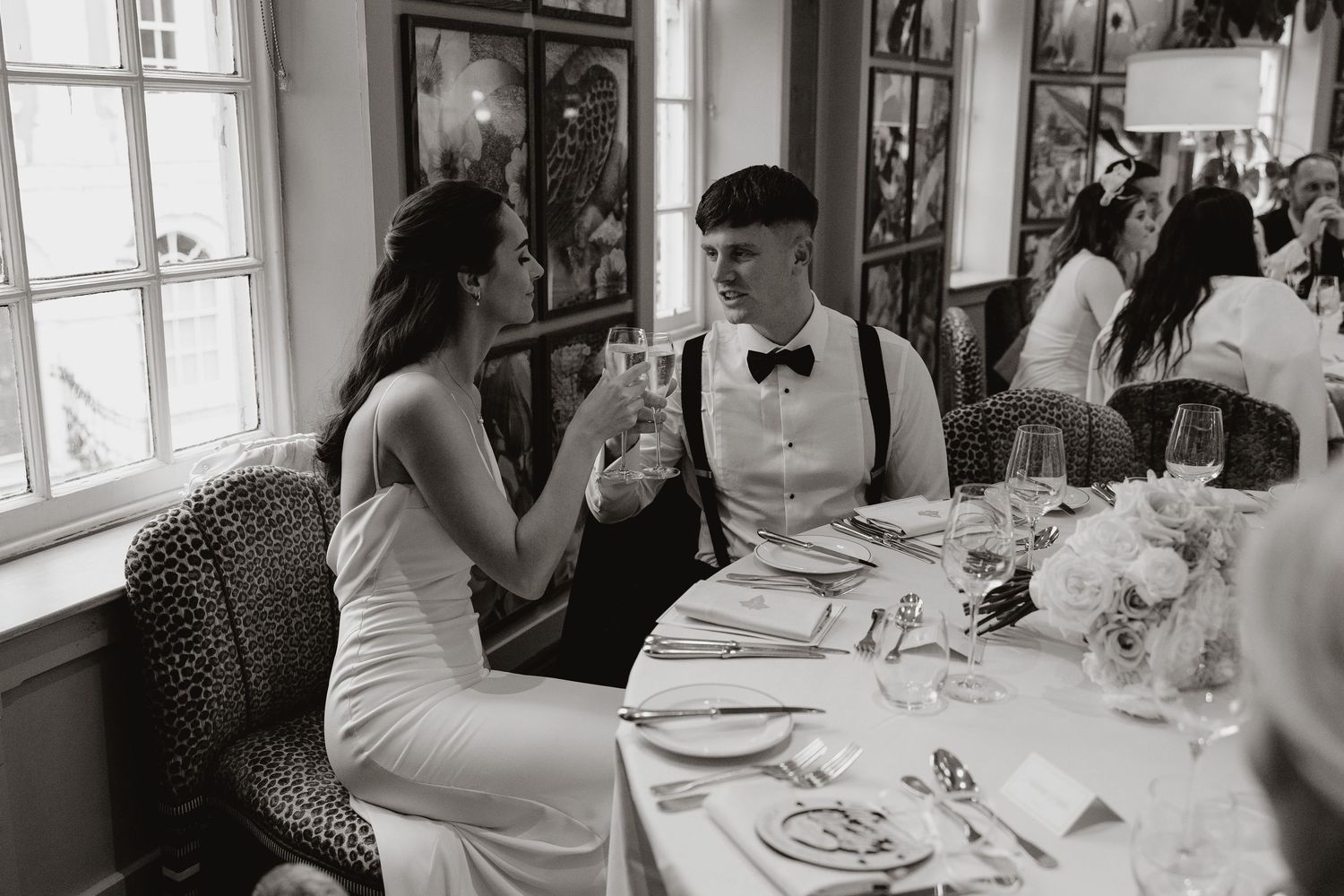 People gather around tables at an elegant dining event in black and white photography.