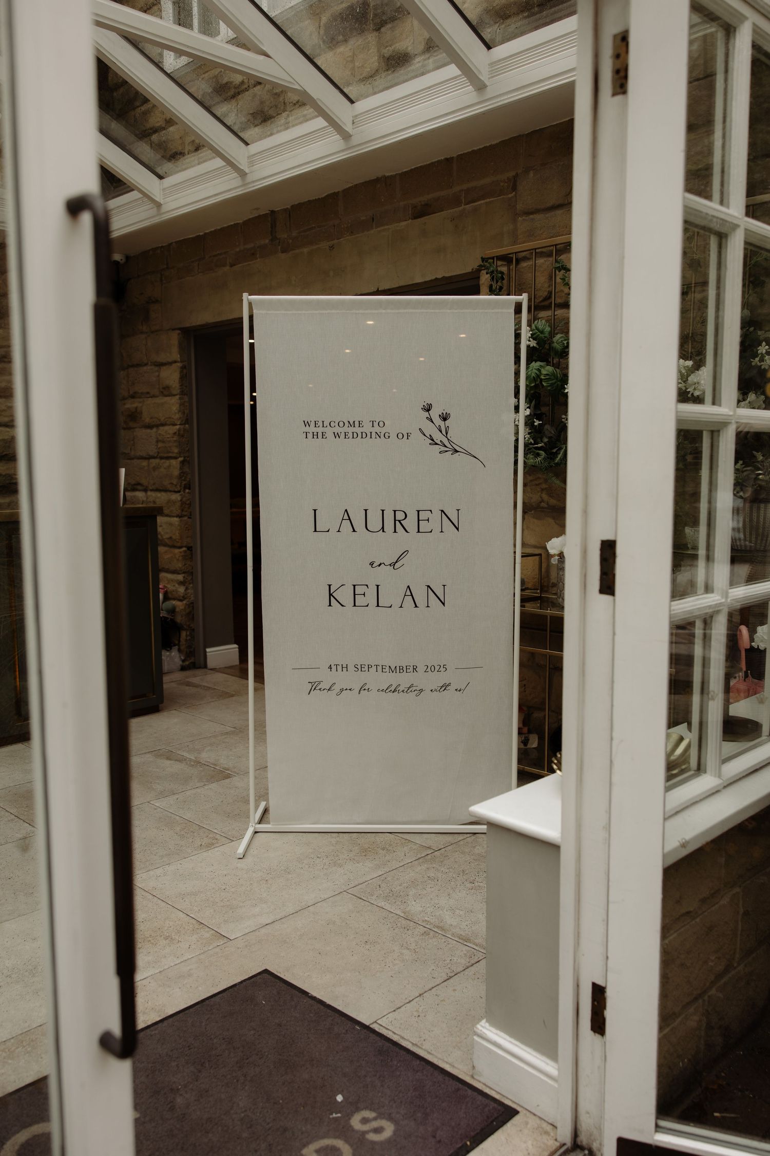 Wedding welcome sign for Lauren and Kelan displayed in an elegant white frame against rustic wood paneling.