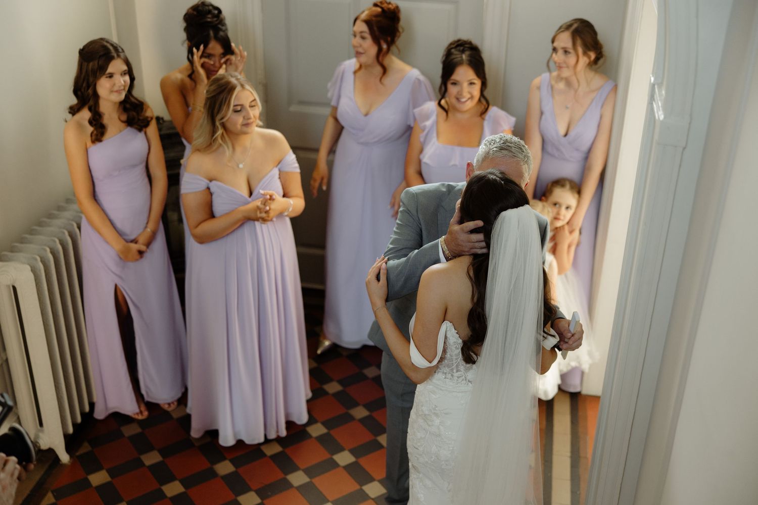 Group of people wearing matching lavender dresses standing together indoors.