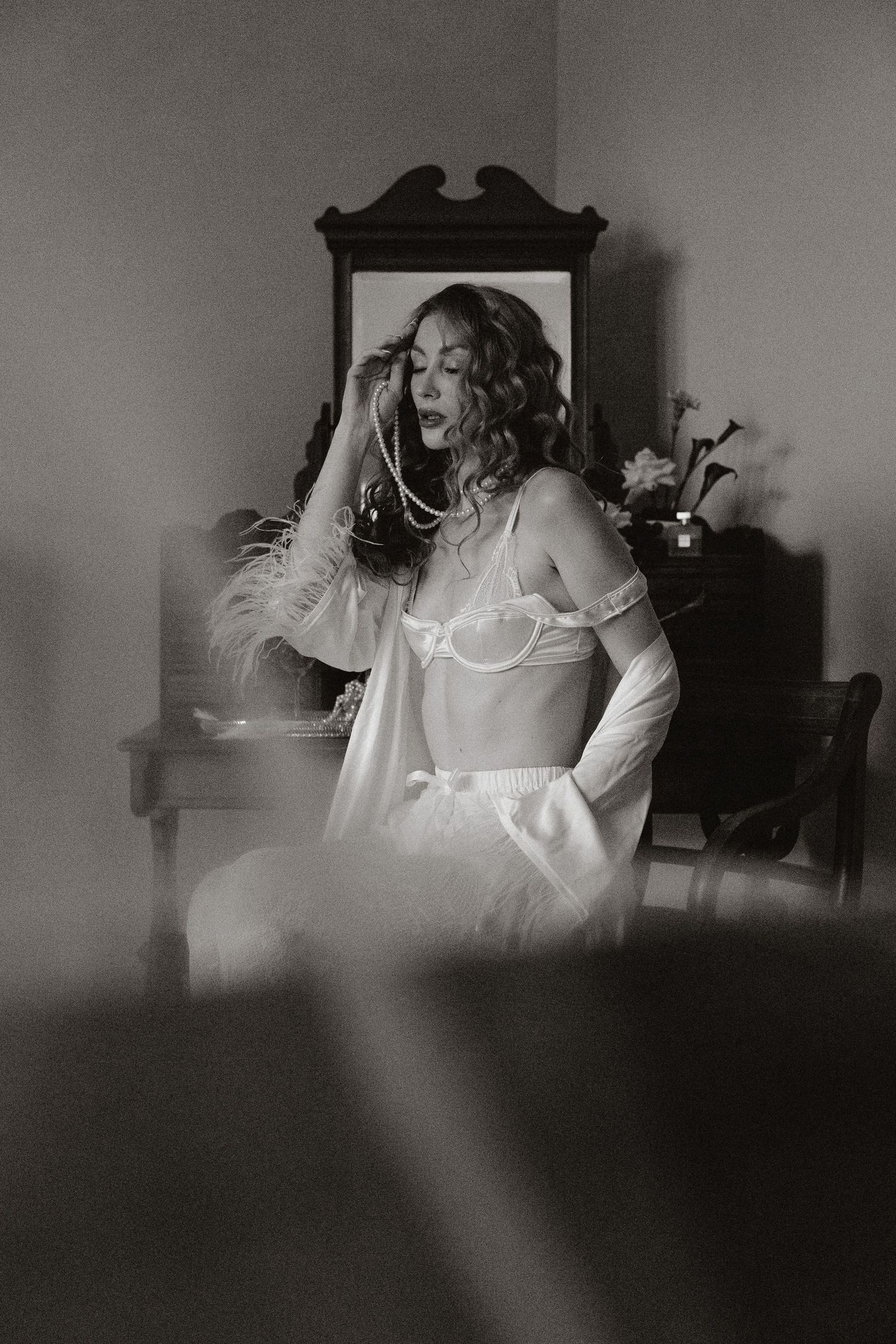 A series of dark and moody black and white photographs showing a figure in white sitting at a desk in dim lighting.