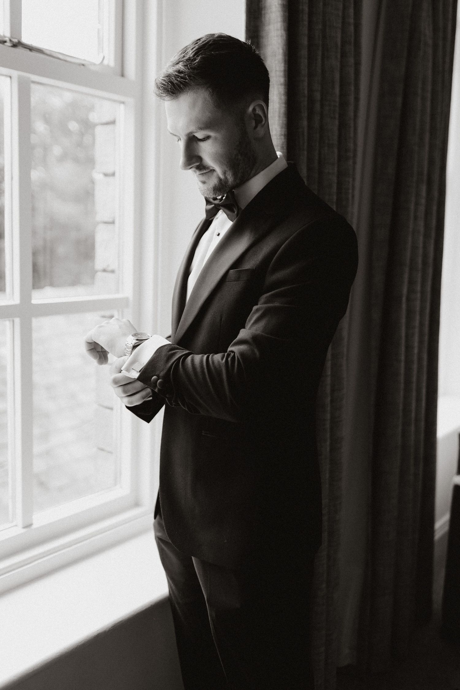 A moody black and white profile silhouette of someone in dark clothing standing next to a bright window.