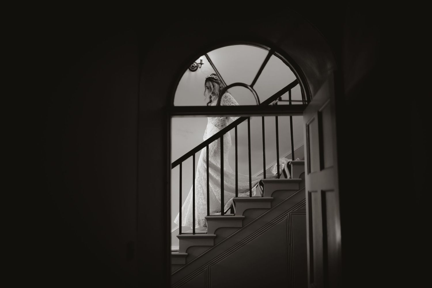 Dark silhouette of a staircase bannister with dramatic shadows and light creating a moody architectural composition.