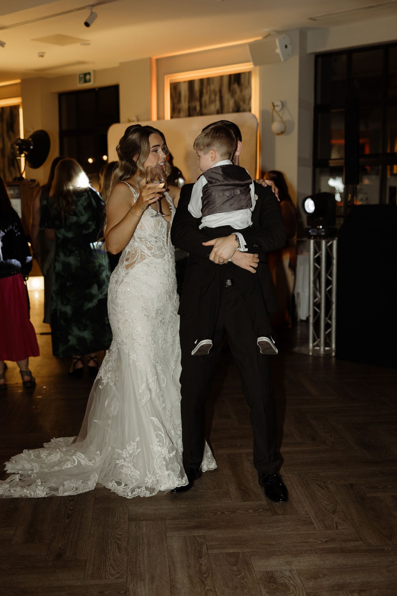Wedding couple dancing together on a dark wooden dance floor at their reception celebration.