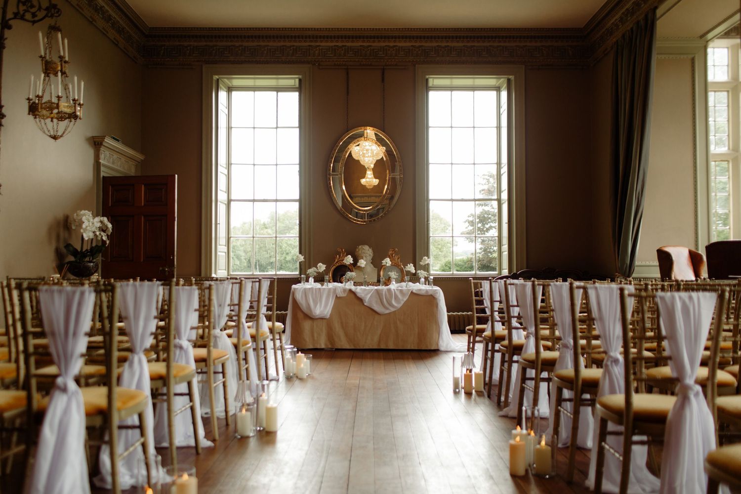 A panoramic view of an elegant wedding reception venue with chandeliers and white-draped chairs in a grand ballroom.