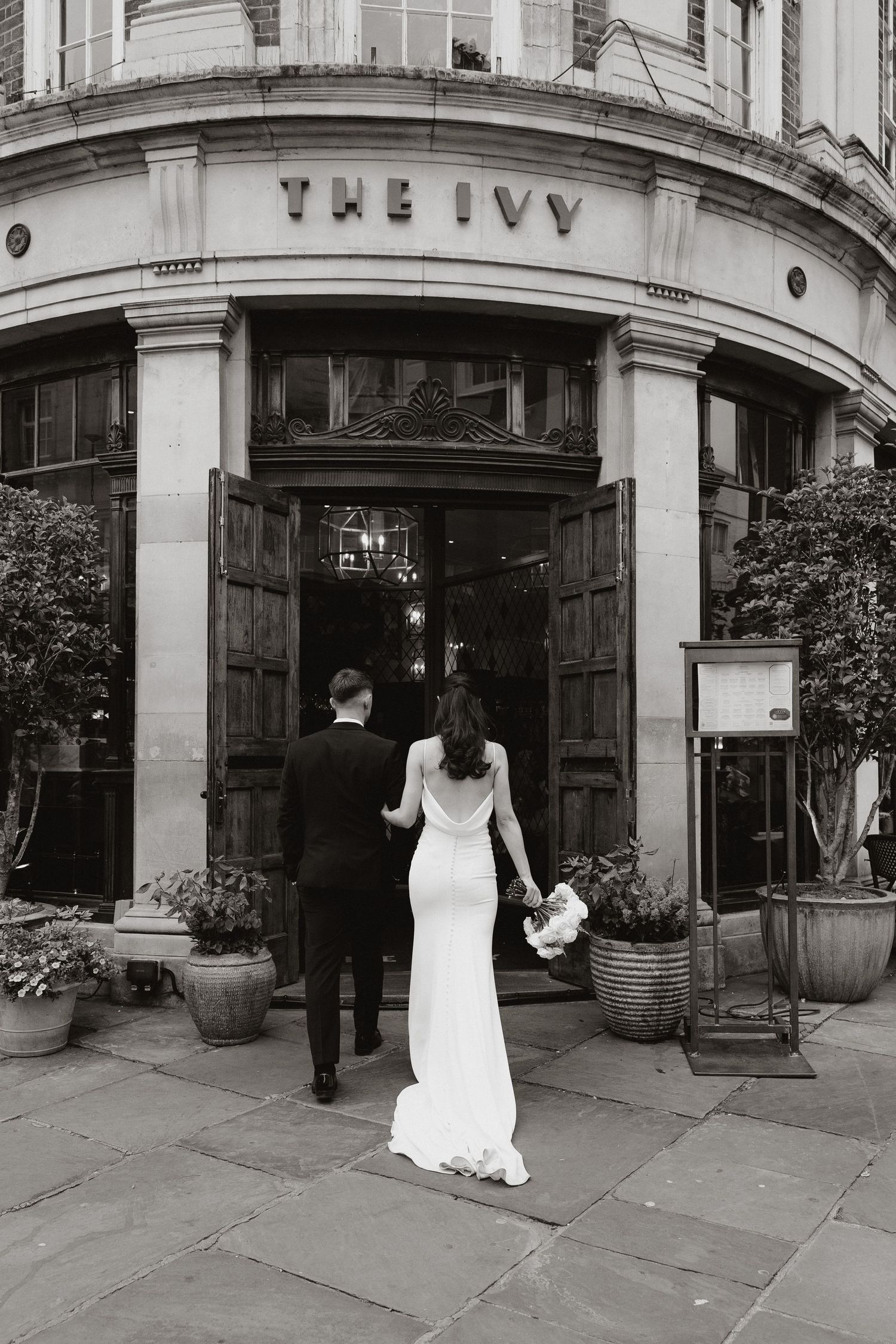 A sequence of black and white photos showing a person in a white dress entering through an elegant doorway marked 'The Ivy'.