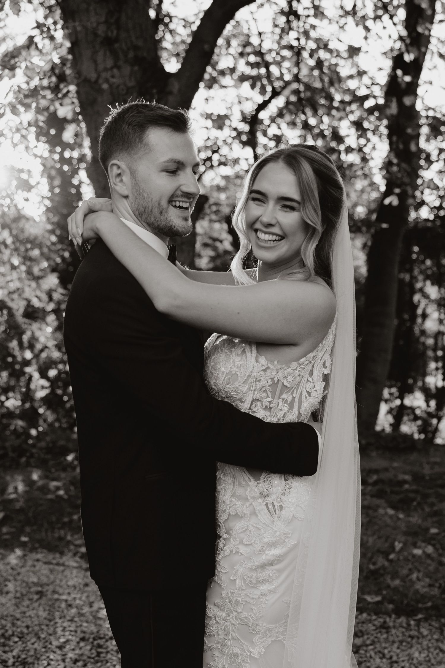 A romantic black and white photo series of a couple dancing together in a wooded outdoor setting during their wedding.