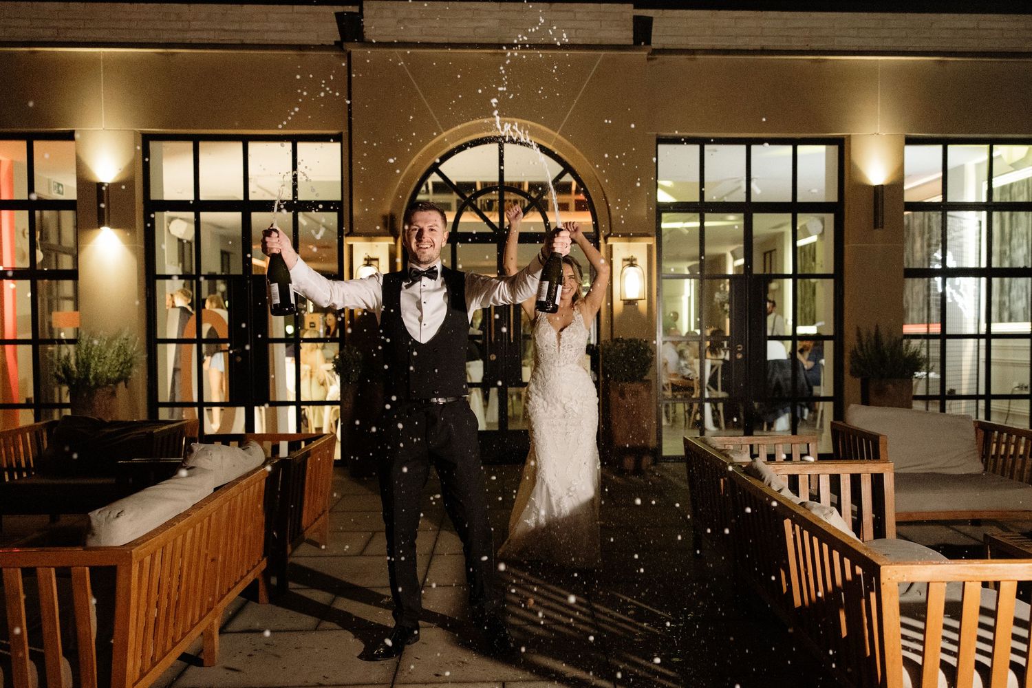 Celebratory moment with confetti falling in an elegant venue with arched windows and warm lighting.
