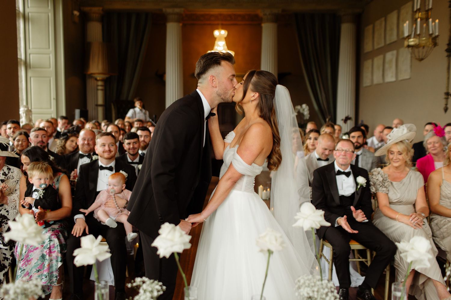 A joyful wedding reception scene with guests dancing and celebrating on a crowded dance floor.