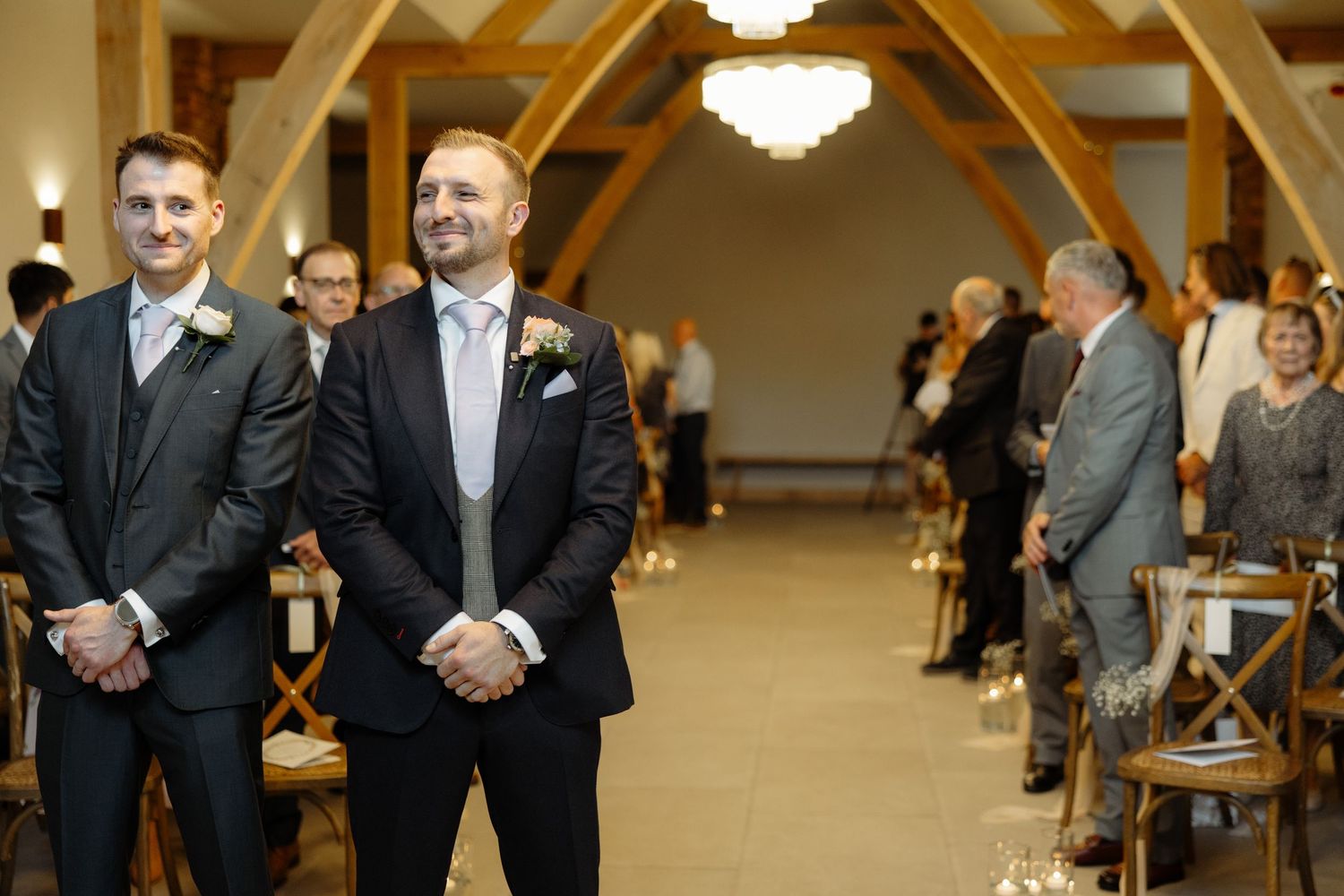 Two people stand at the altar during a wedding ceremony in an elegant venue with exposed wooden beams.