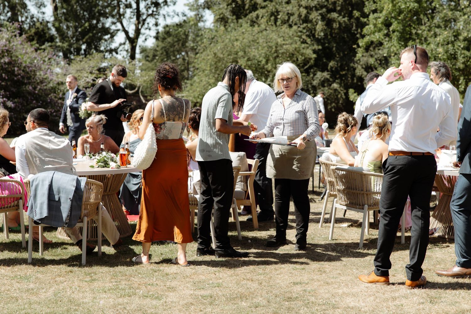 A group gathers outdoors for a casual event with chairs arranged in rows on a sunny day.