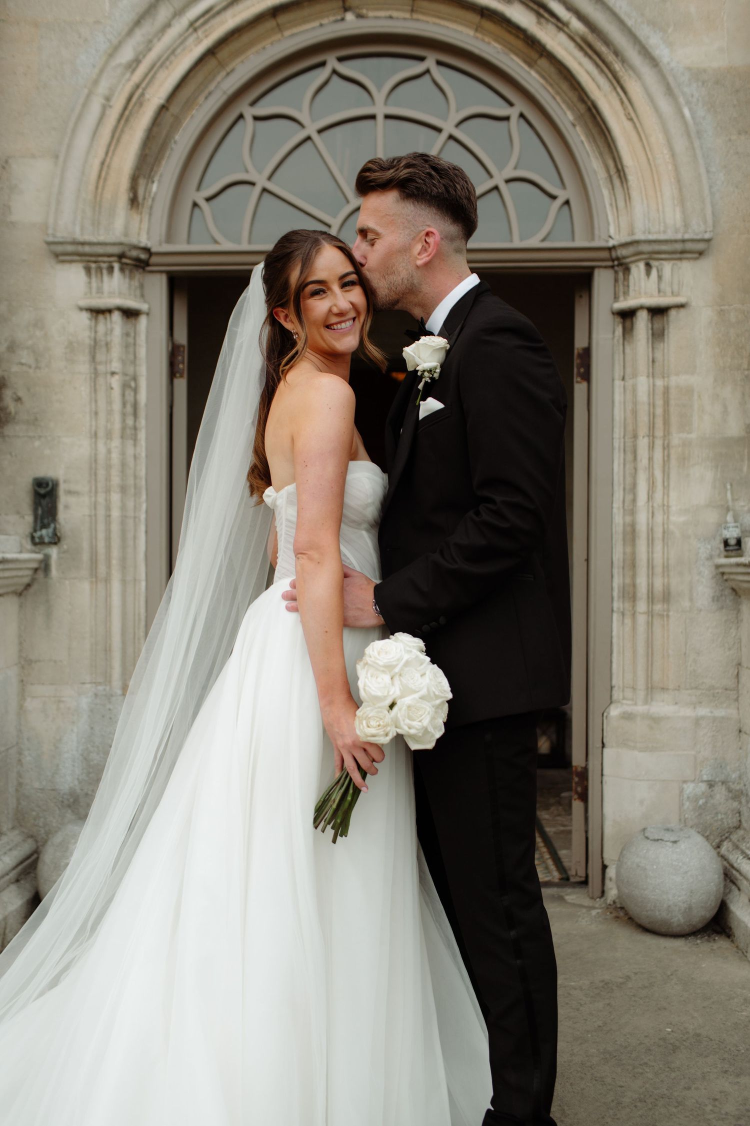 A romantic sequence of newlywed couple posing in front of Gothic church doorways with white flowers and formal attire.