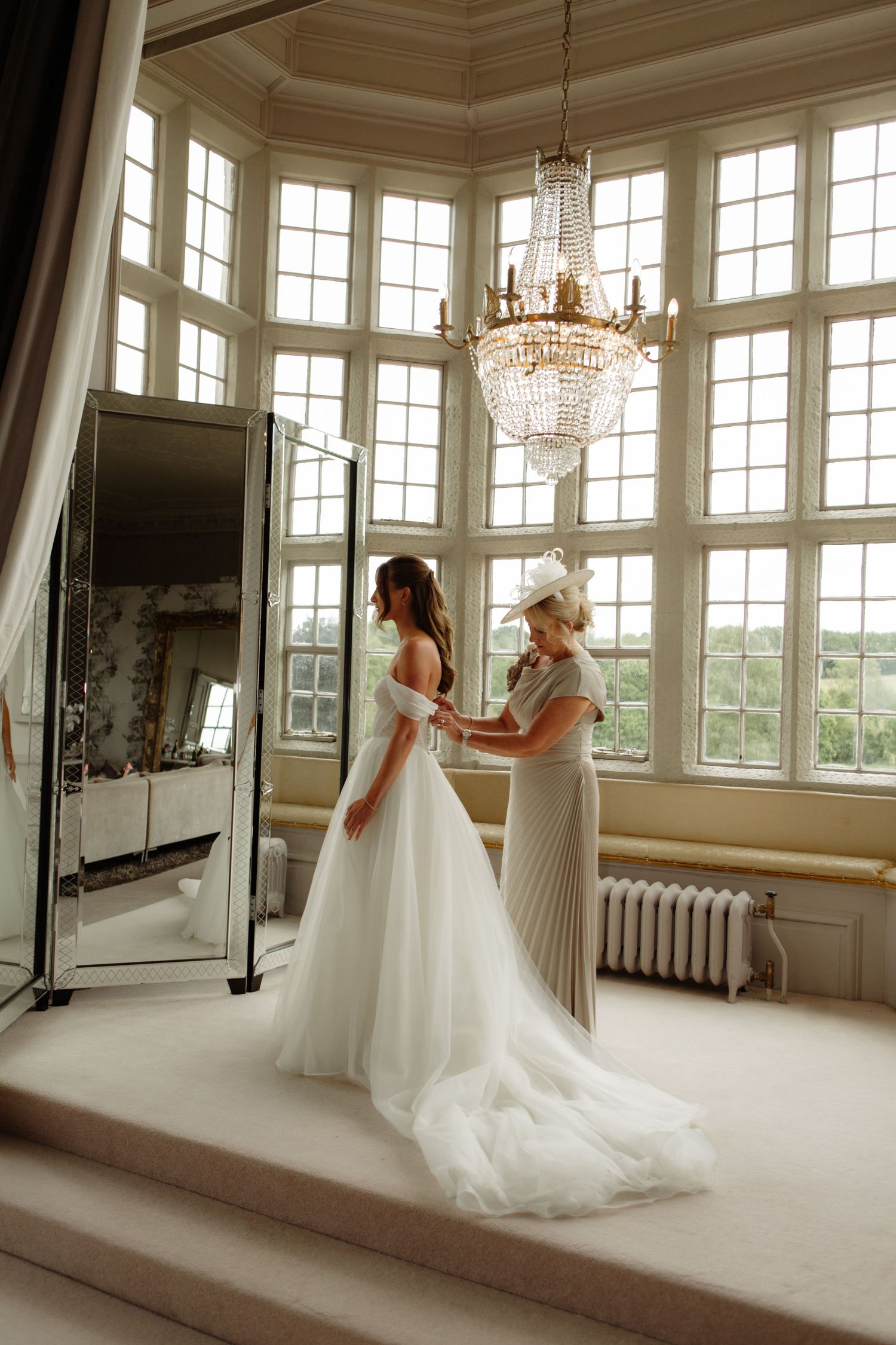 Elegant bridal portraits captured in a sunlit room with crystal chandeliers and large windows.