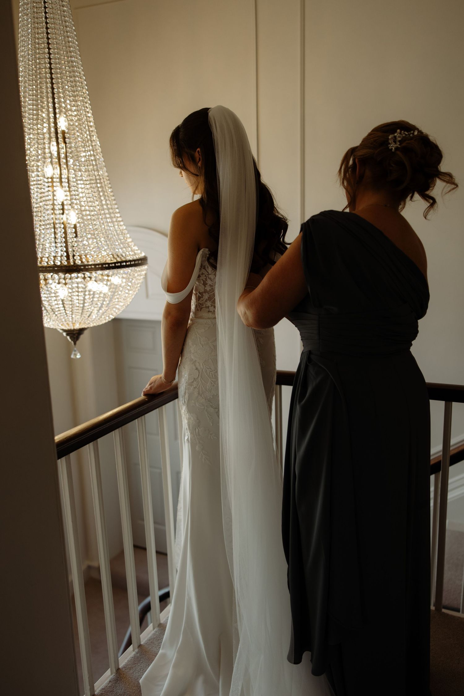 A group of people in black and white formal attire stand together under a crystal chandelier in an elegant setting.