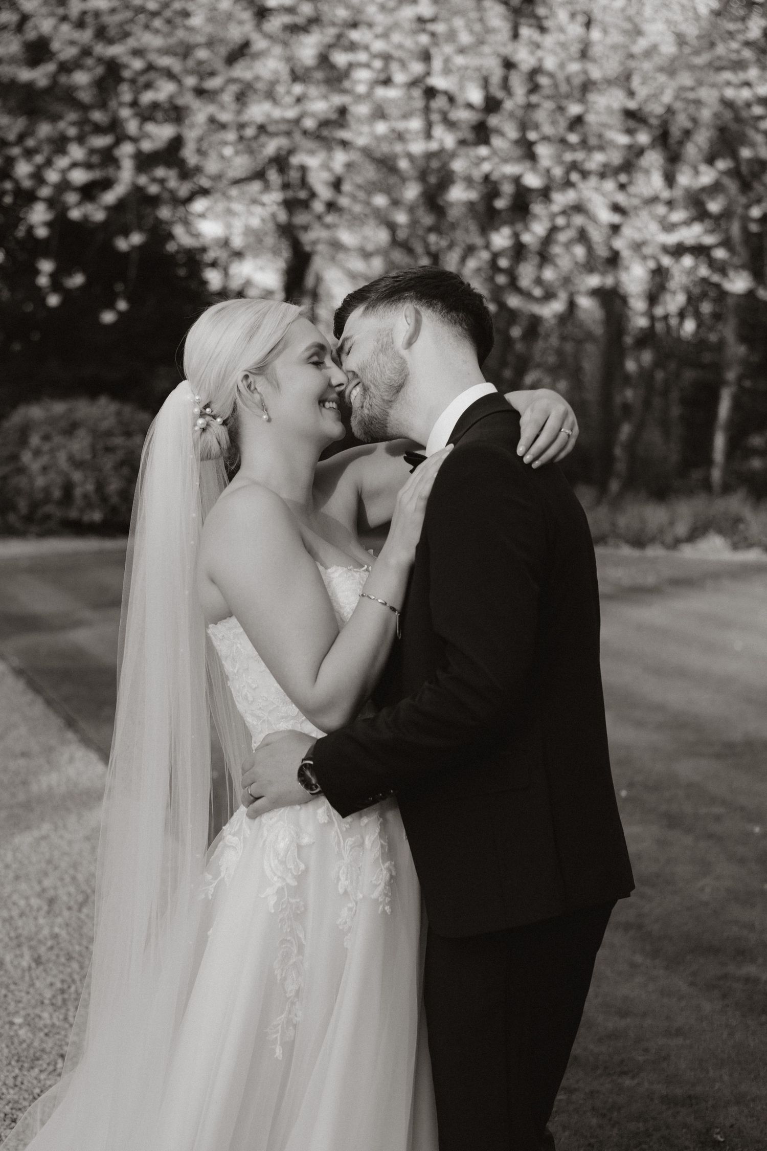 A romantic outdoor wedding photoshoot showing tender moments between a couple in a blooming garden setting.