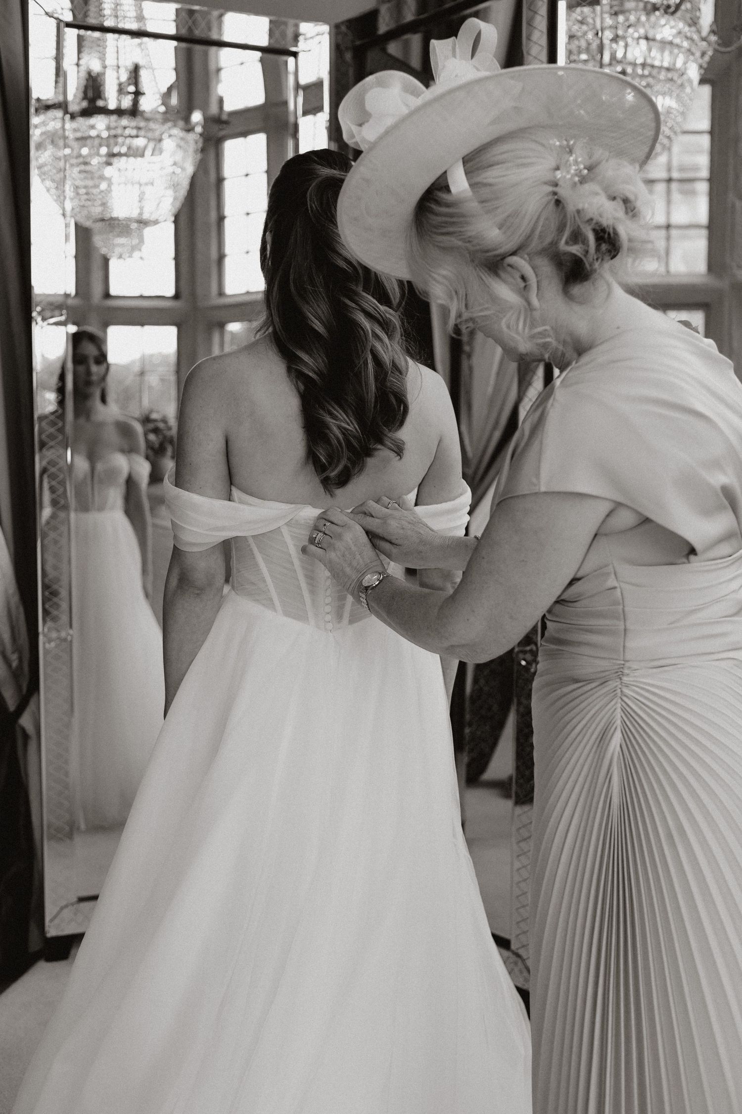 Wedding party assists with dress preparations in black and white photo sequence.