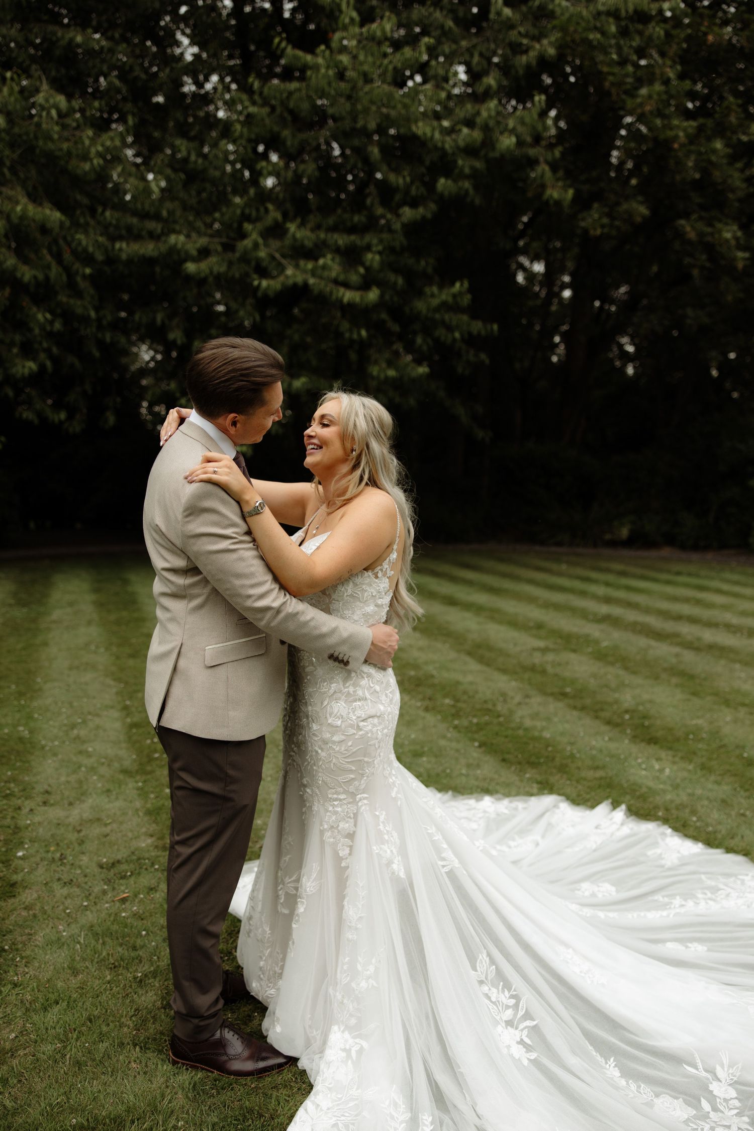 A couple dances together during their wedding celebration on a manicured lawn in elegant formal attire.