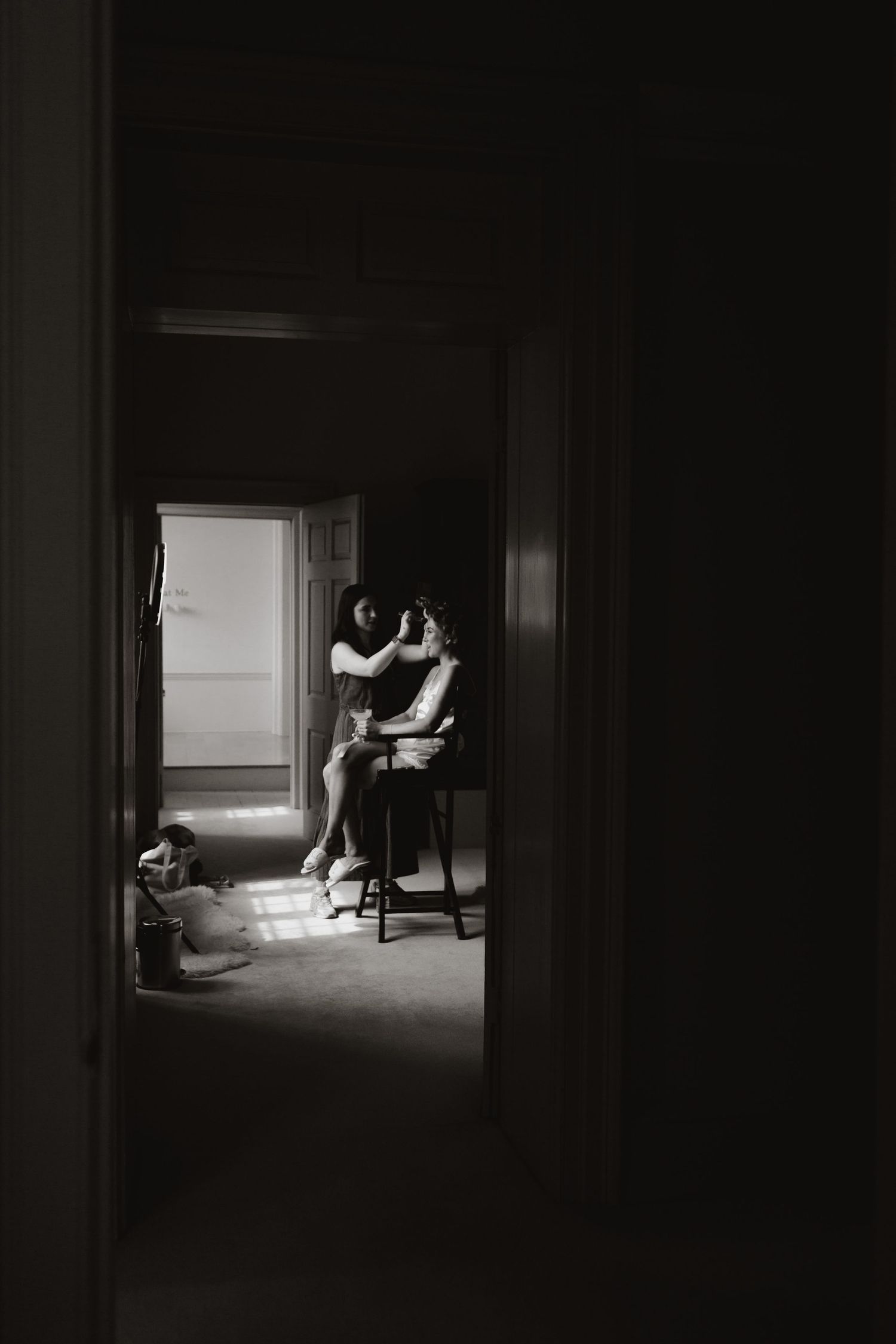 A series of moody black and white photographs depicting two silhouetted figures in a dimly lit room by a window.