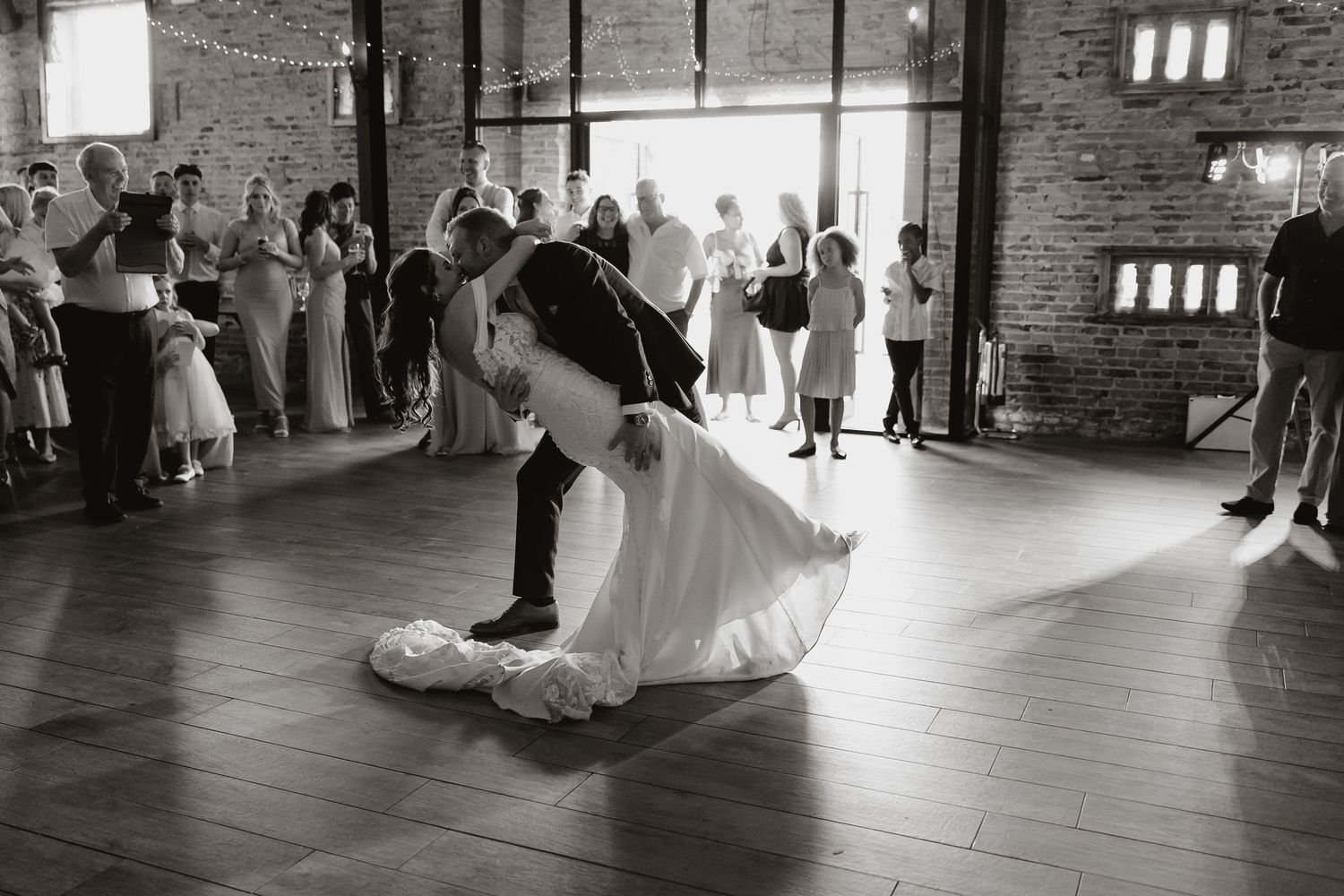 A black and white series of wedding dance floor moments captured in an industrial brick venue space.