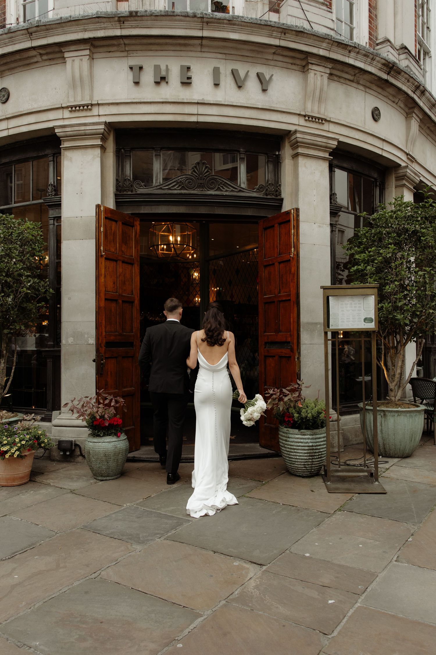 A sequence of wedding photos showing a couple entering through grand wooden doors at The Ivy restaurant entrance.