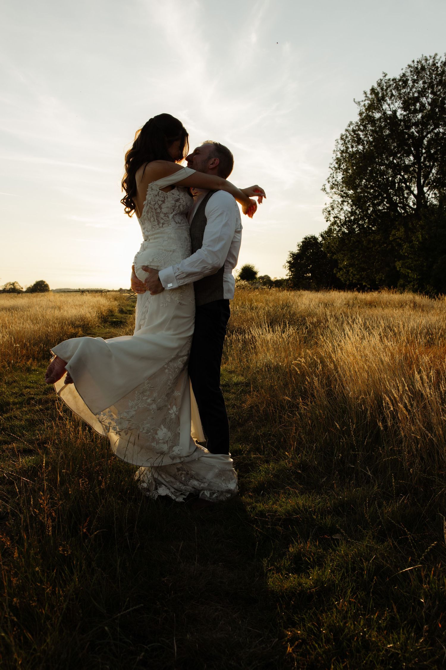 Silhouetted couple dancing and twirling in a golden field at sunset, creating a romantic and dreamy atmosphere.