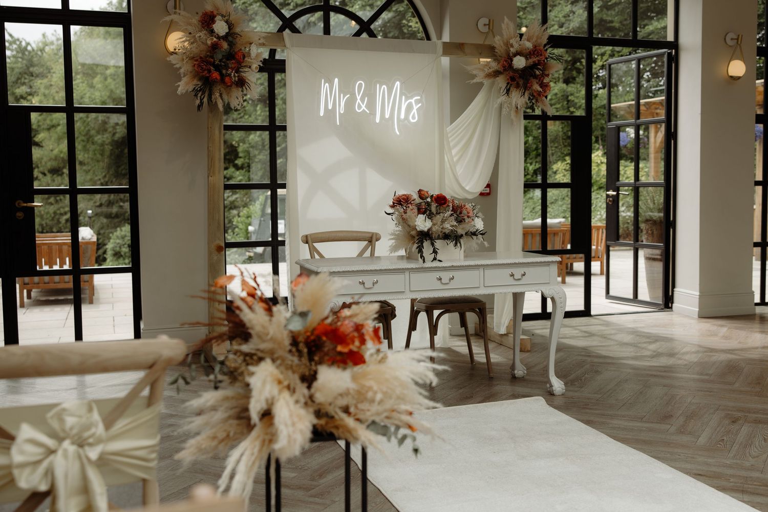 A bright, modern wedding venue with large windows, white columns, and floral arrangements set up for a reception.