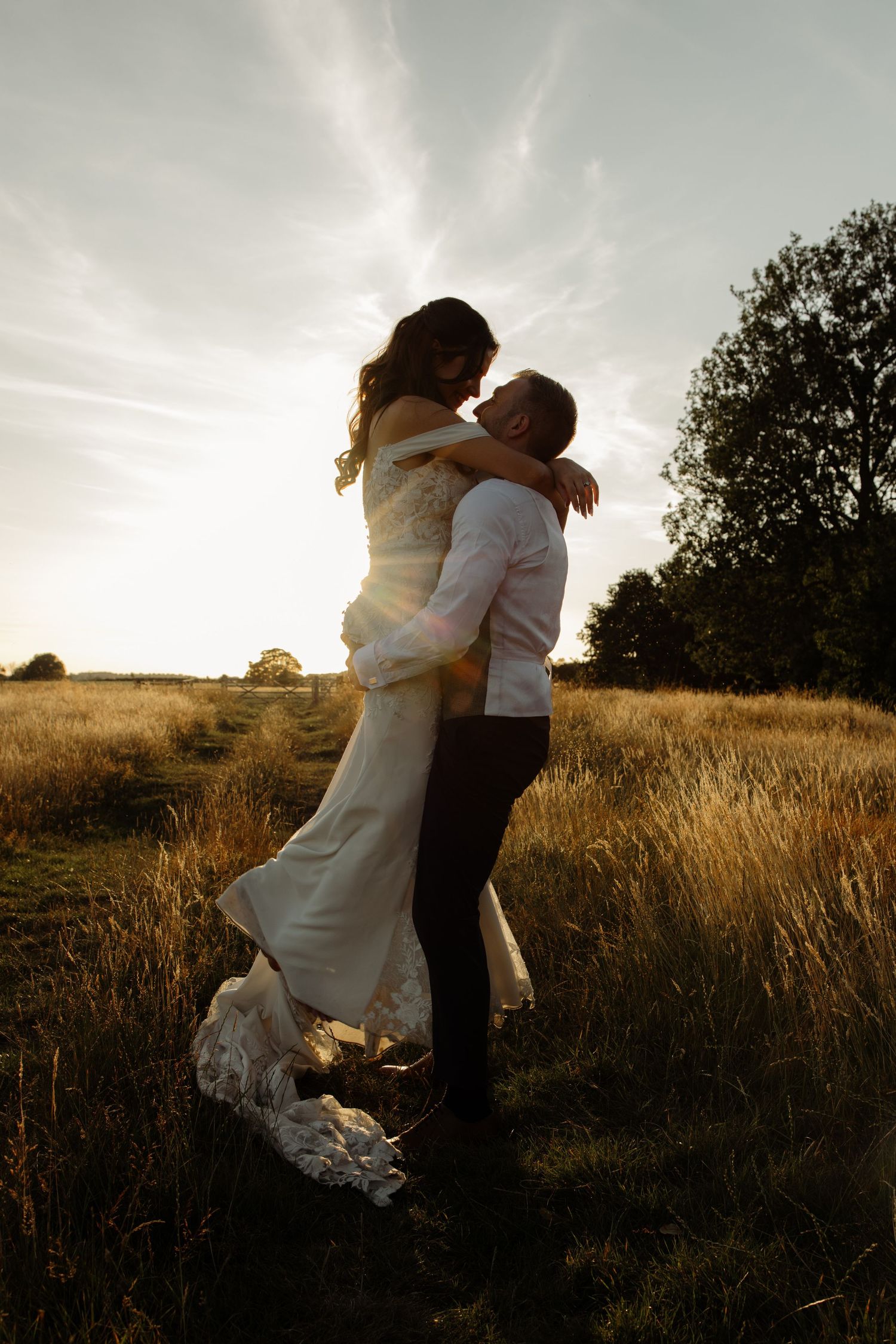 Romantic silhouettes of a couple embracing in a sunlit meadow during golden hour.