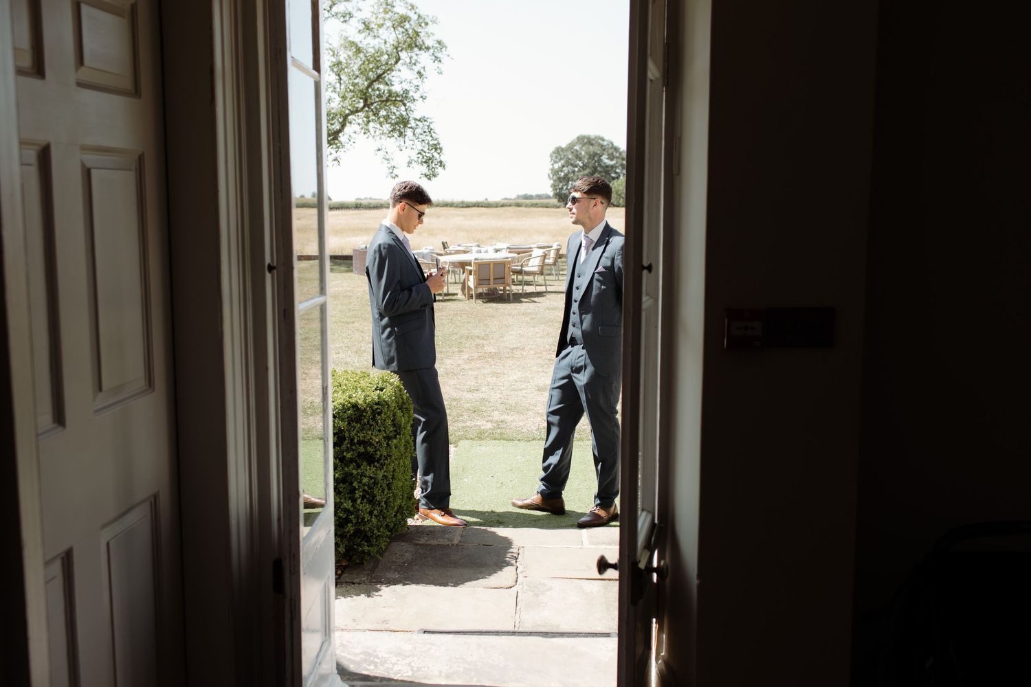 Two people in business attire stand in a doorway having a conversation.