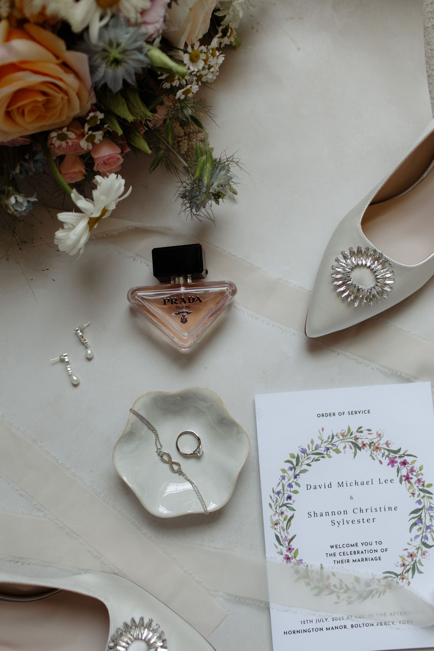 Wedding details including floral arrangements, invitations with delicate botanical designs, and elegant accessories on a light surface.