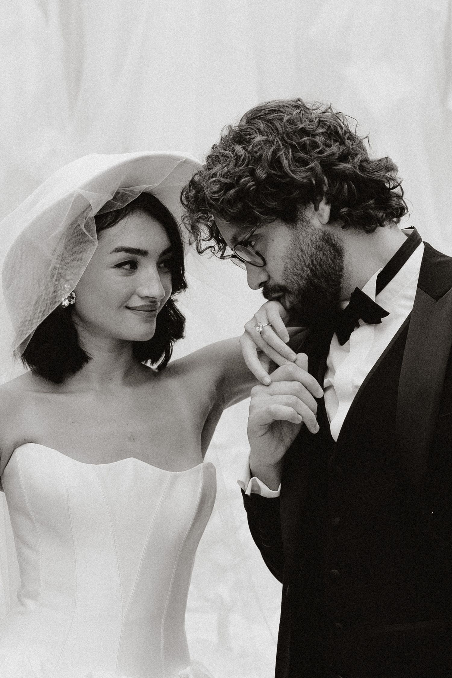A romantic black and white wedding photo showing a bride in a strapless gown and groom in a tuxedo sharing an intimate moment.