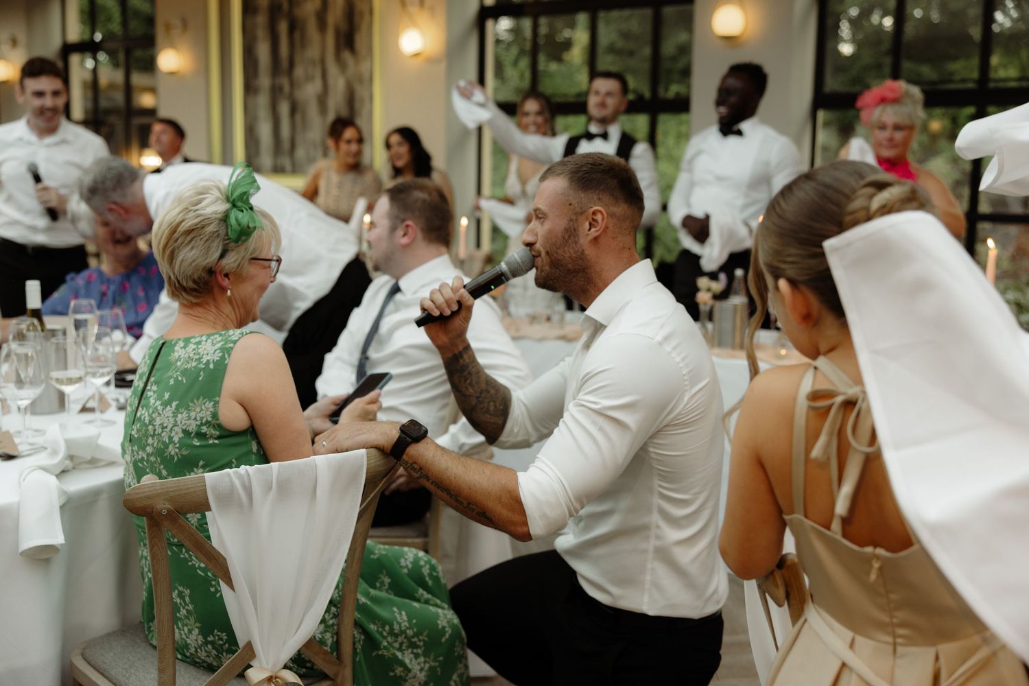 Wedding guests in formal attire enjoying conversation during an elegant indoor reception dinner.