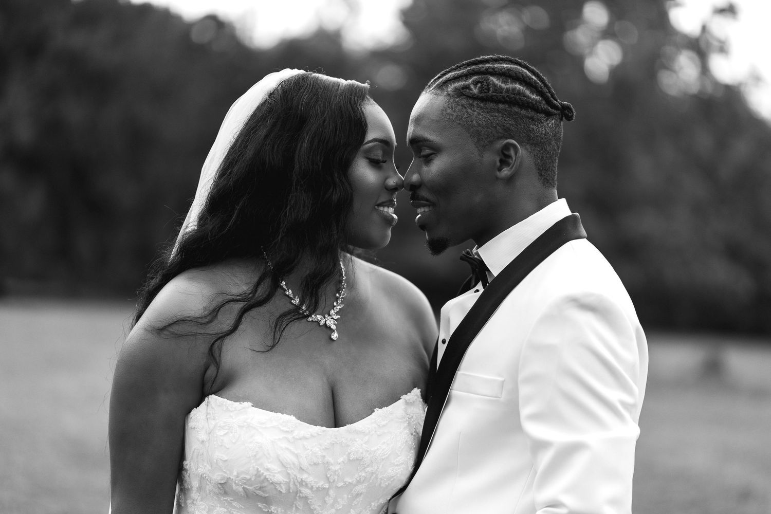 Black and white photo of bride and groom sharing a romantic moment outdoors on their wedding day.