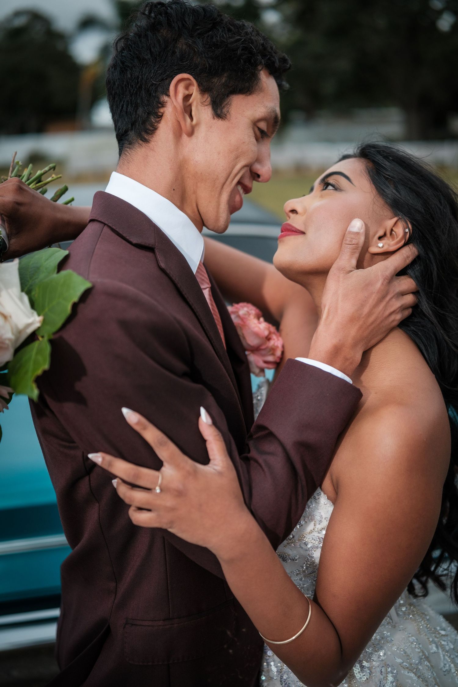 A romantic moment between newlyweds in formal wedding attire sharing an intimate embrace outdoors.