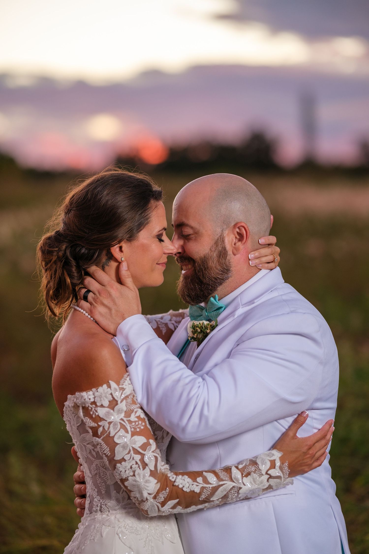 Romantic sunset wedding photos show a couple embracing in a field during golden hour.