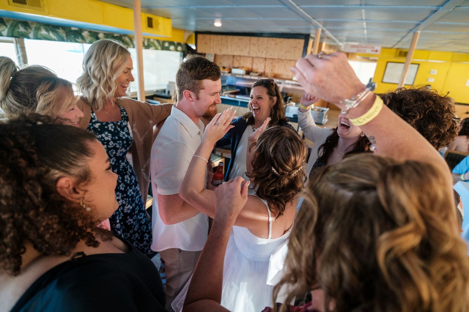 Wedding reception celebration with guests dancing under yellow tent covering.