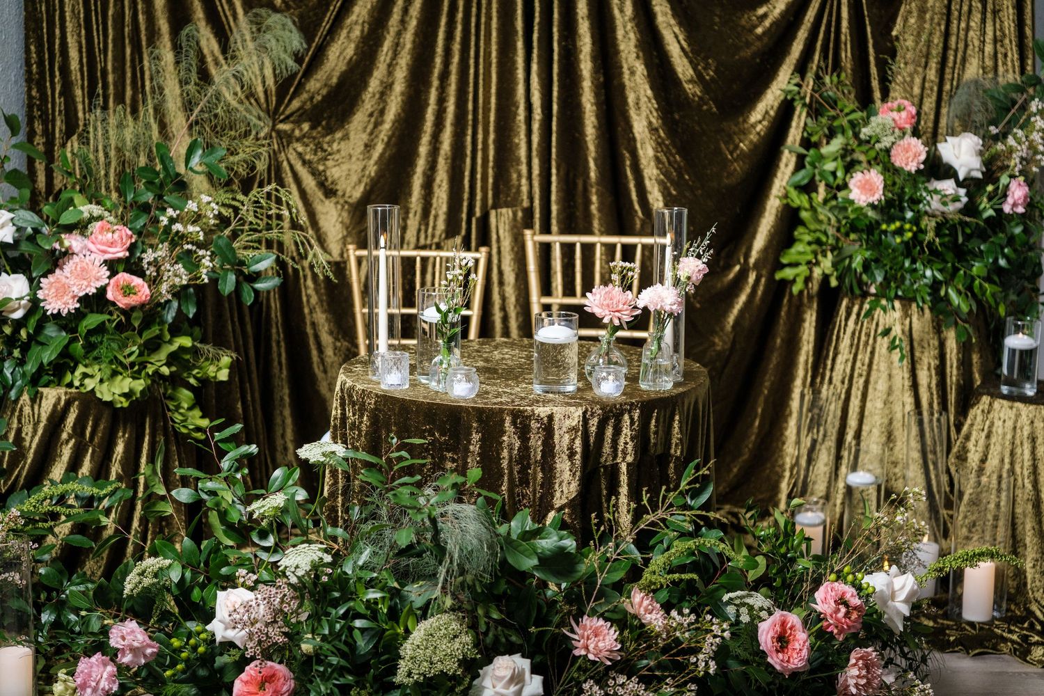 Pink roses bloom near wooden lanterns and banyan trees creating an enchanting garden setting.